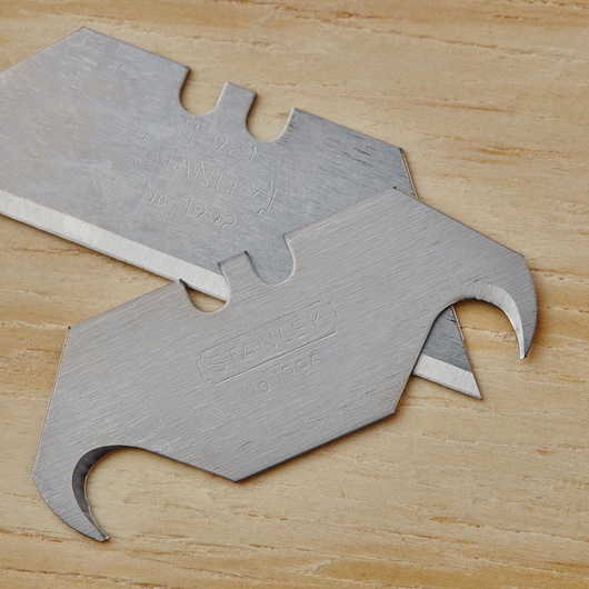 STANLEY 10-099 utility hook blades, close-up on flat wooden surface.