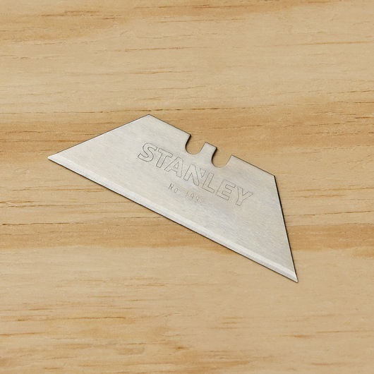 STANLEY 11-921 utility knife blade, silver, single blade shown on wood background, angled top view.