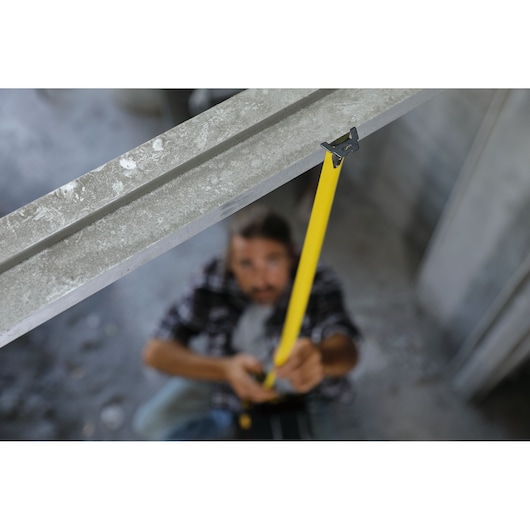 STANLEY 30-626 yellow tape measure in use on metal beam, construction context, close-up photography.