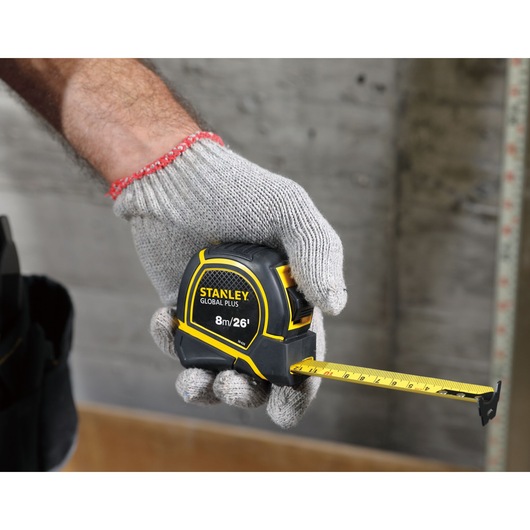 STANLEY 30-626 tape measure held by gloved hand, yellow and black casing, measurement extended.