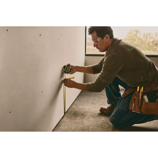 STANLEY 30-626 tape measure in use, shown measuring a wall by a worker wearing a tool belt.