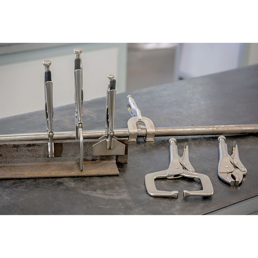 Photo of STANLEY 84-399 locking pliers and clamps on a metal workbench, showcasing various types in use.