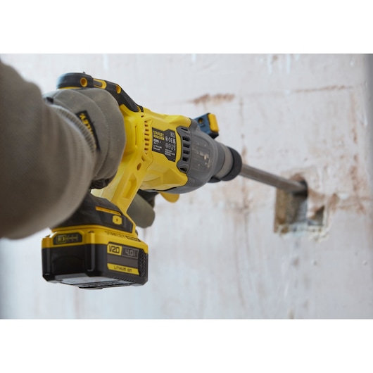 STANLEY SBH900M2K-B3 rotary hammer in use drilling into a concrete wall, close-up side view.