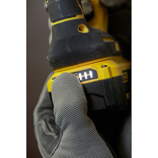 STANLEY SBH900M2K-B3 power tool battery pack close-up, glove pressing LED indicator, side angle.