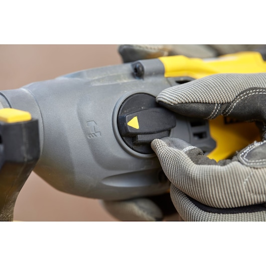 STANLEY SBH900M2K-B3 rotary hammer mode selector close-up, gray and yellow, gloved hand adjusting switch.