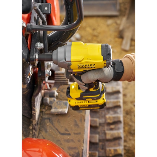 Stanley SBW920M2K impact wrench used to tighten bolts on machinery, shown in close-up, outdoors.
