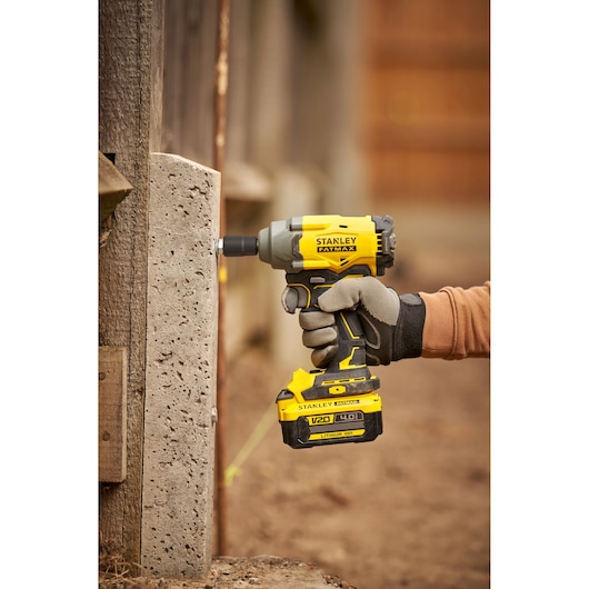 Photo of STANLEY SBW920M2K impact driver being used on concrete, side view, yellow and black tool.