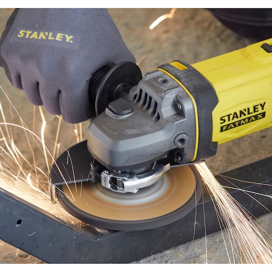 STANLEY SCG400M2K-KR angle grinder in use, emitting sparks while cutting metal, close-up side angle.
