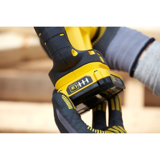 STANLEY SCR300D2K cordless tool base and battery in close-up, black and yellow design, worker gloves visible.