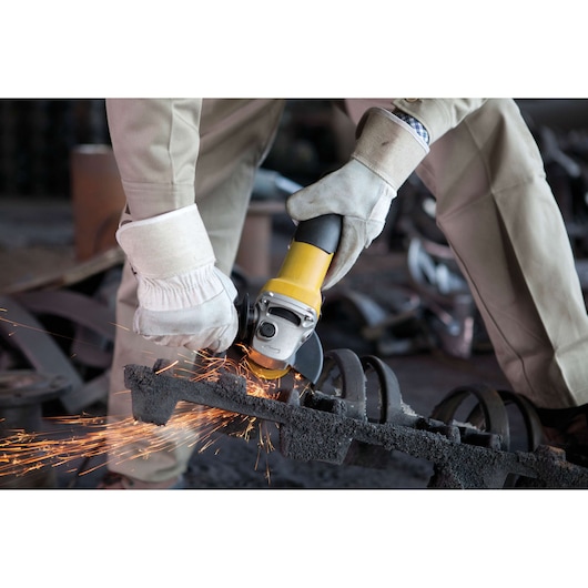 Photo of STANLEY SGS1045K angle grinder in use, producing sparks, person wearing gloves operating tool.