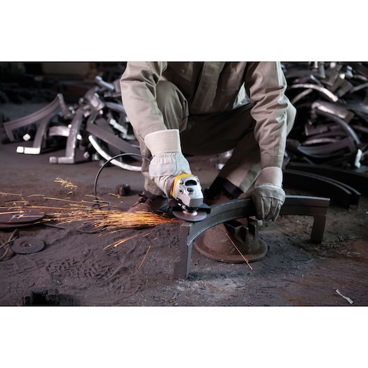 STANLEY SGS1045K angle grinder in use, worker cutting metal with sparks flying, industrial setting.