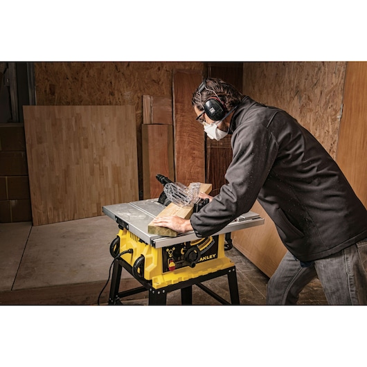 Stanley SST1801-B3 table saw in use, yellow body, wood cutting in workshop setting.