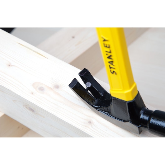 Stanley STHT51391 claw hammer removing nail from light wood, close-up angle.