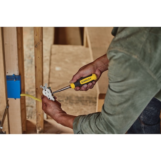 Photo of a person using a STANLEY STHT60083-LA screwdriver on an electrical outlet during wiring installation.