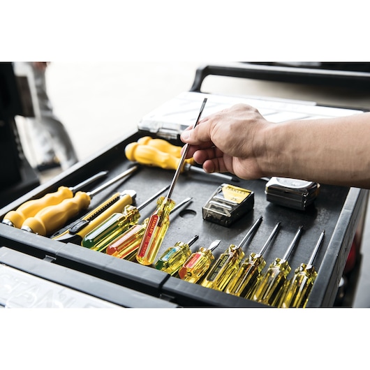 STANLEY STHT69112 screwdriver set with yellow handles on a workbench, hand selecting a tool, perspective view.
