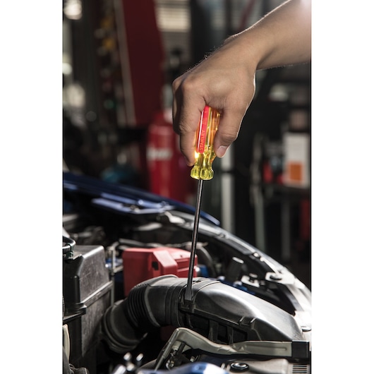 Stanley STHT69120 screwdriver with yellow handle used in car engine, close-up side photography.