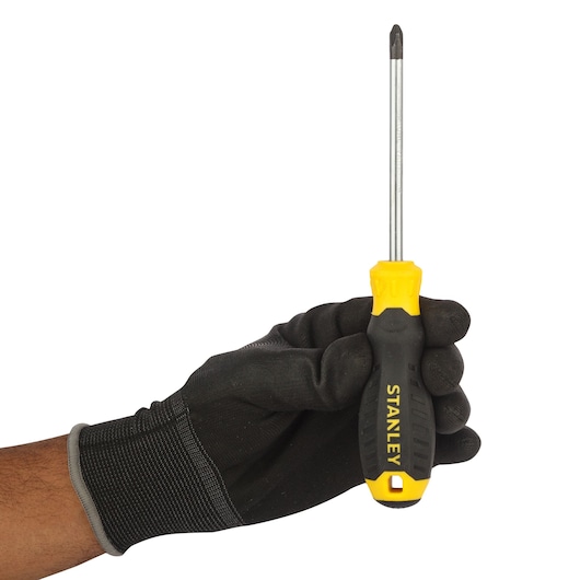 Photo of STANLEY STMT60809-8 black and yellow Phillips screwdriver held in a gloved hand, side angle.