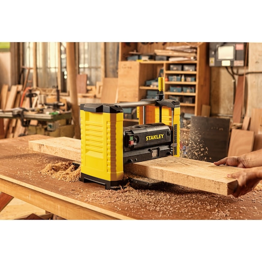 STANLEY STP18-B2 planer in use on wood plank, woodworking shop background, front angle.