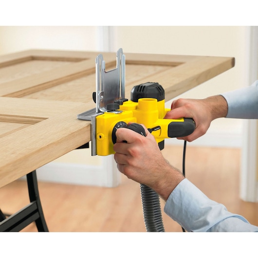 STANLEY STPP7502-B2 planer in use trimming a wooden door, close-up view, product photography.