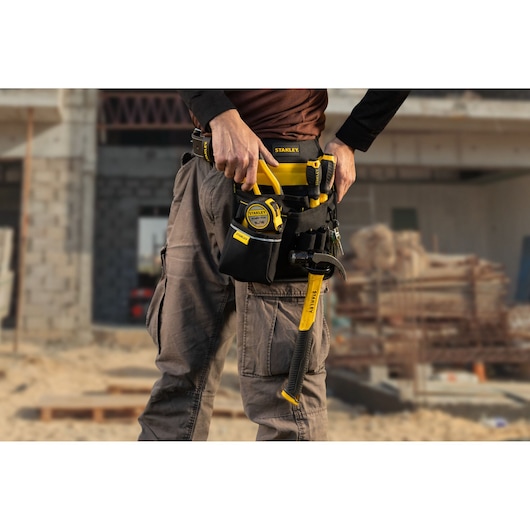Photo of STANLEY tool belt STST511324LA with tools, worn on waist at construction site.